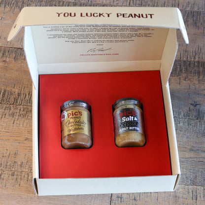 Two jars of pickle relish in a box labeled 'You Lucky Peanut' on a wooden surface.
