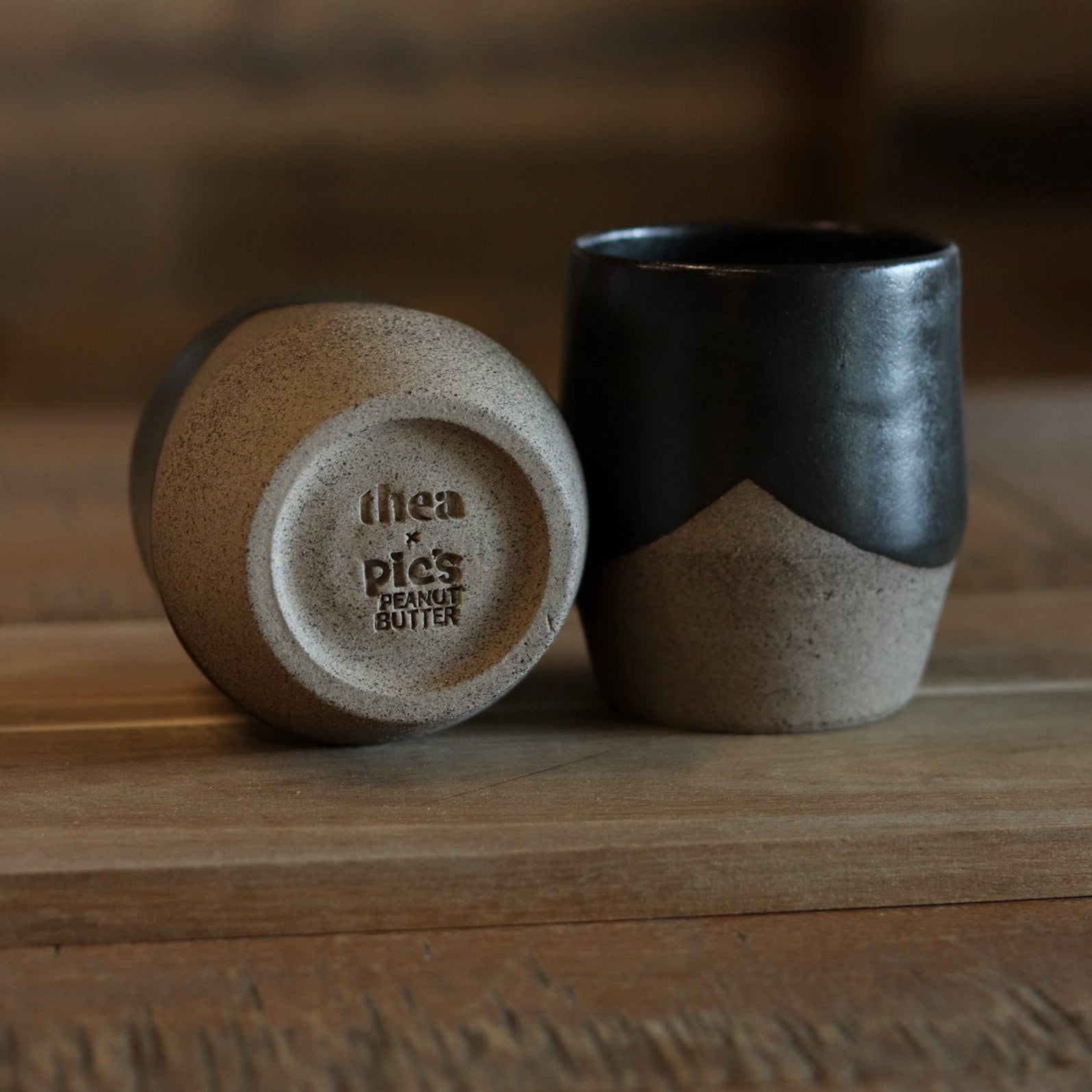 Two ceramic cups on a wooden surface with a blurred background