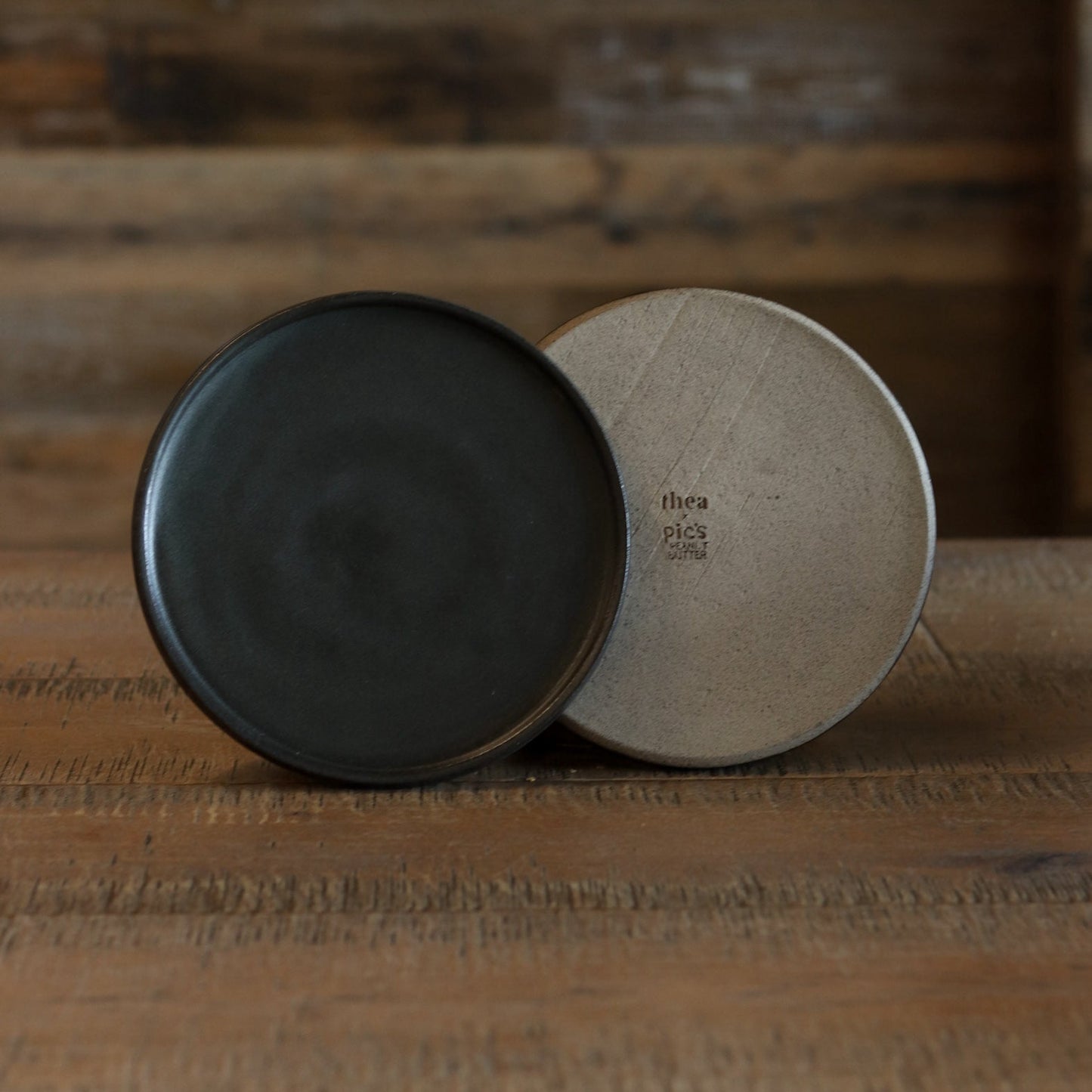 Two ceramic bowls, one black and one beige, on a wooden surface with a blurred wooden background.