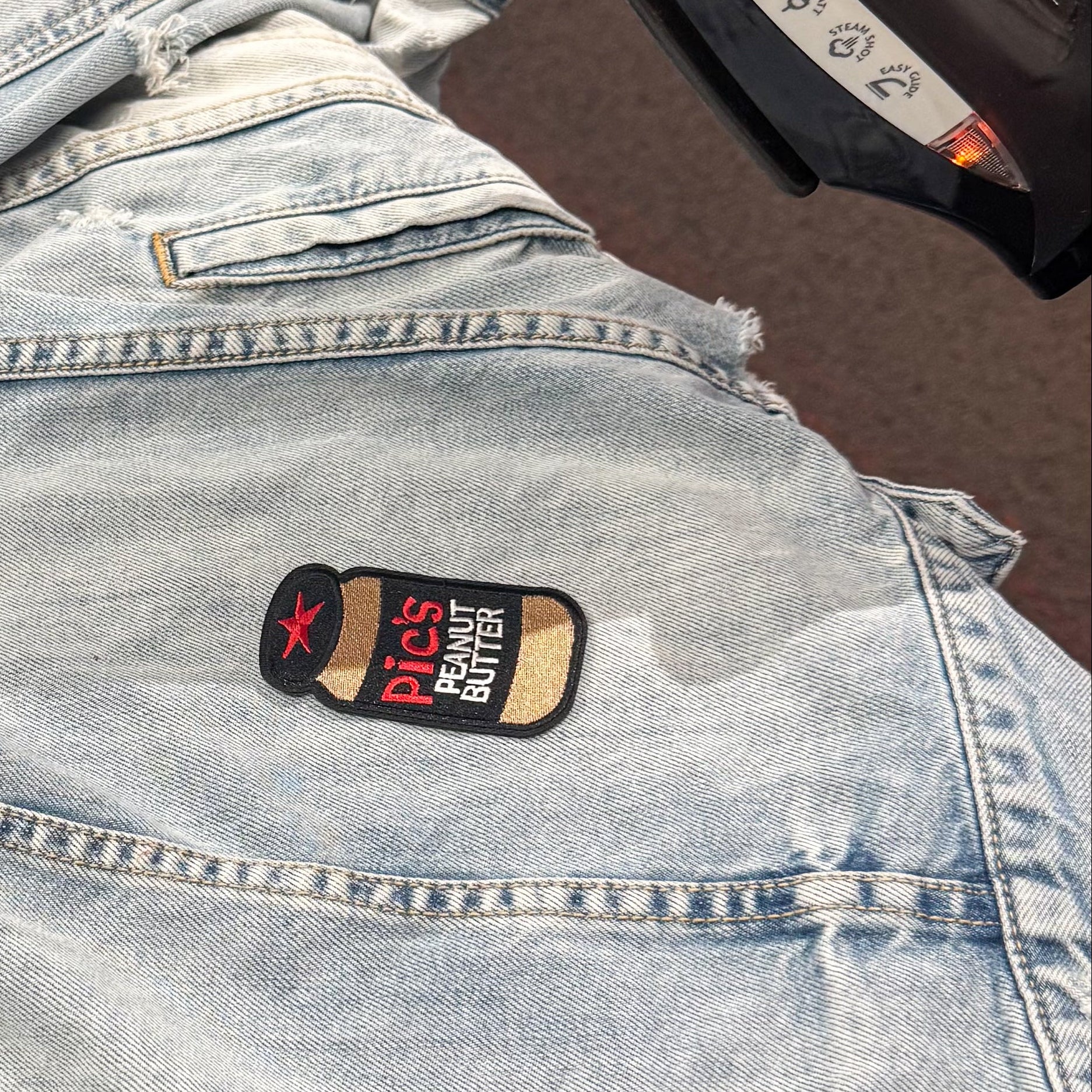 Ironing a patch on a denim jacket with a close-up of the iron.